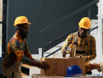 African american people packing boxes with products, preparing stock for shipment order. Young storage room employees putting merchandise in cardboard packages, goods on racks.
